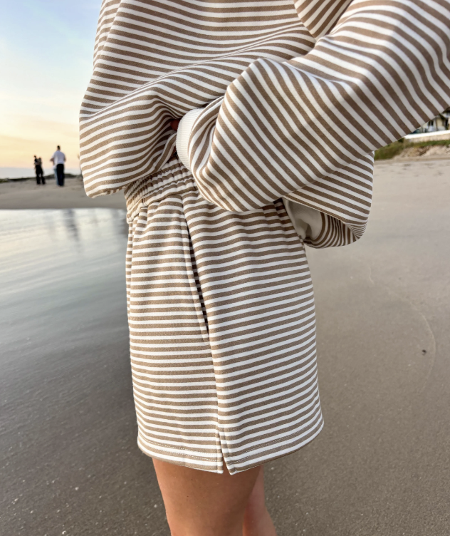 Woman wearing matching brown and white stripe set on the beach
