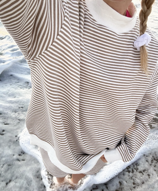 Woman wearing brown and white stripe pullover on the beach