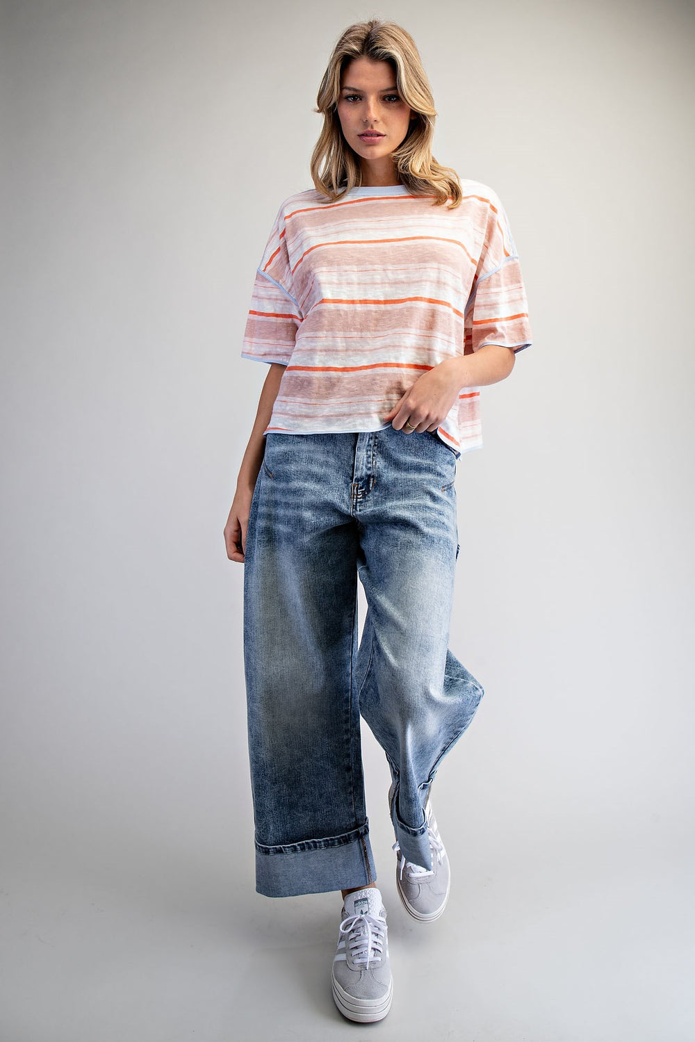Woman wearing a striped shirt and jeans on a plain background