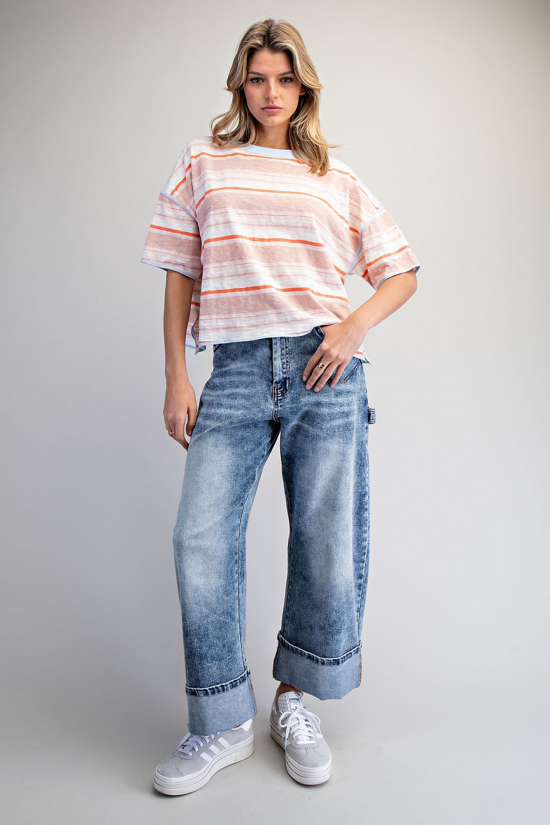 Woman wearing a striped shirt and blue jeans on a gray background