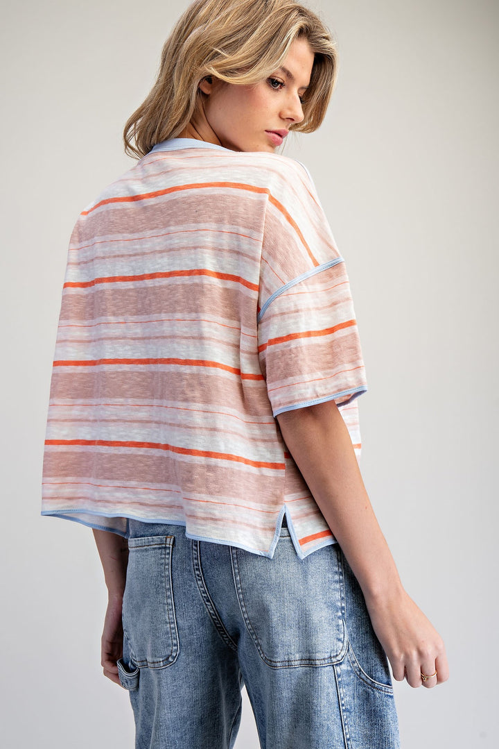 Woman wearing a striped shirt and jeans on a plain background