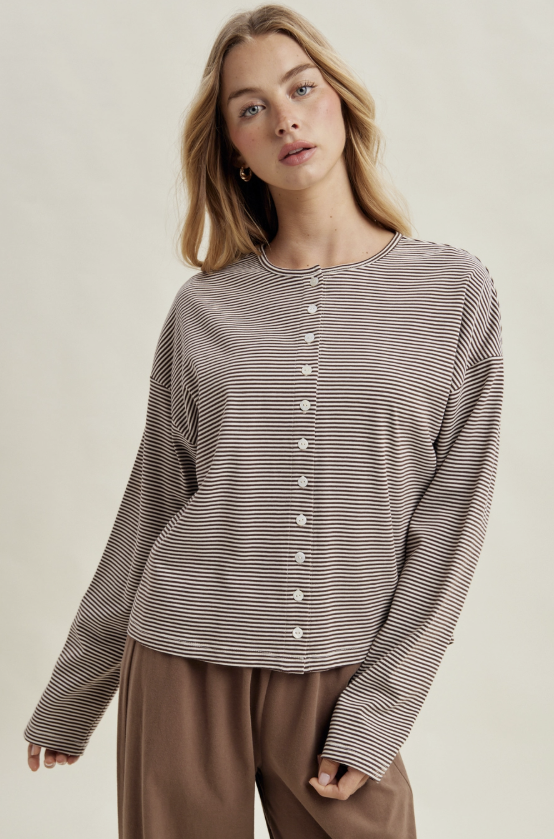 Woman wearing brown and white stripe cardigan with brown pants on plain background