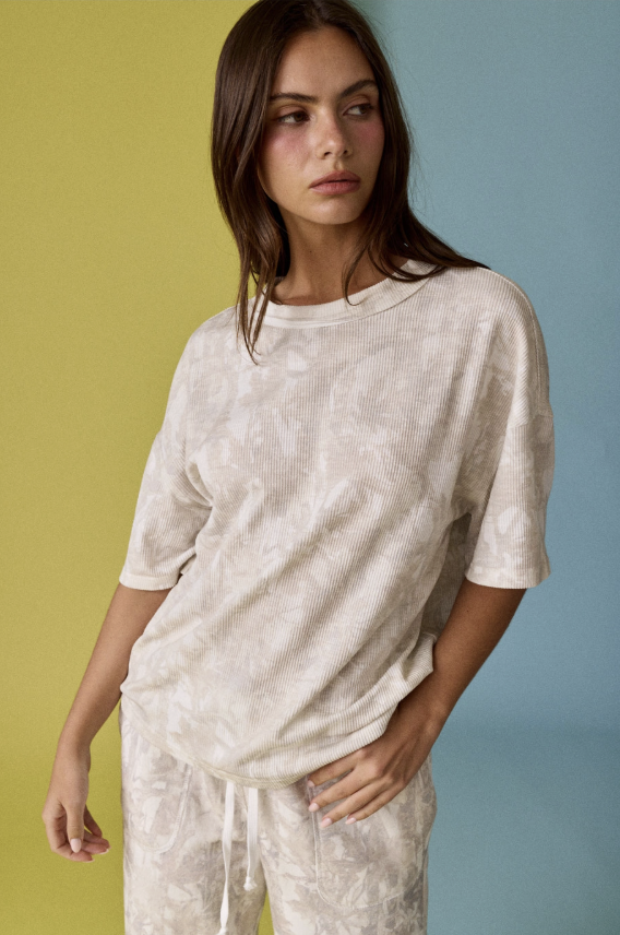Woman wearing a beige knit top and pants against a multicolored background