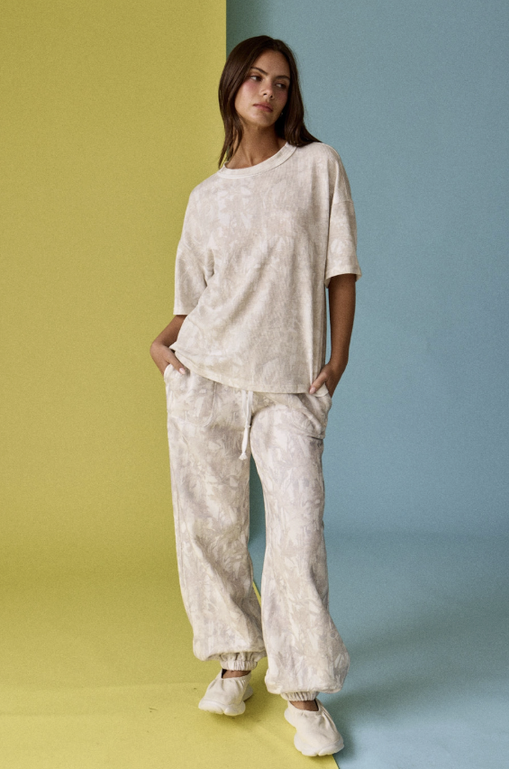 Woman wearing a beige outfit against a split yellow and blue background