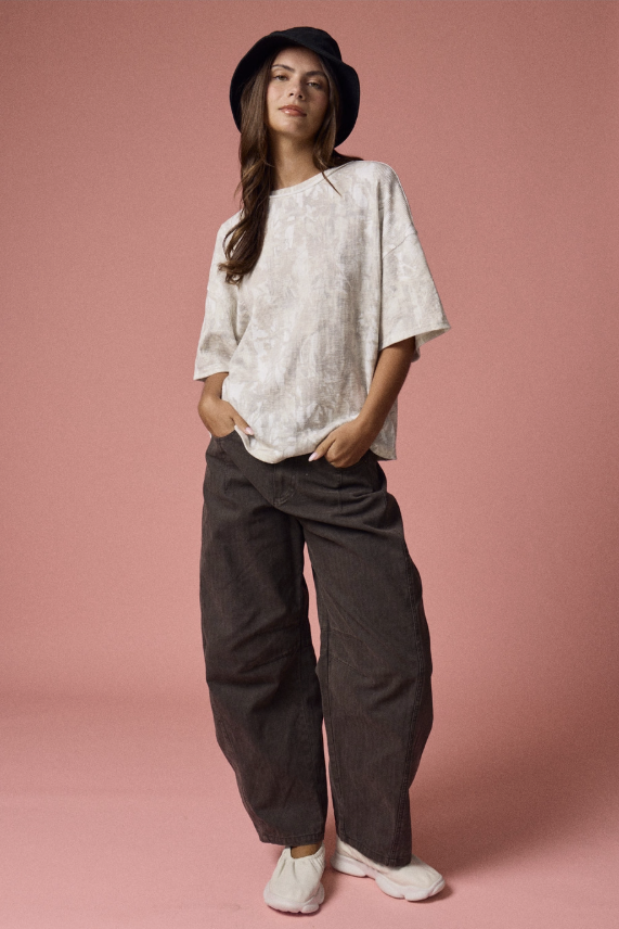 Woman wearing a white top and dark pants against a pink background