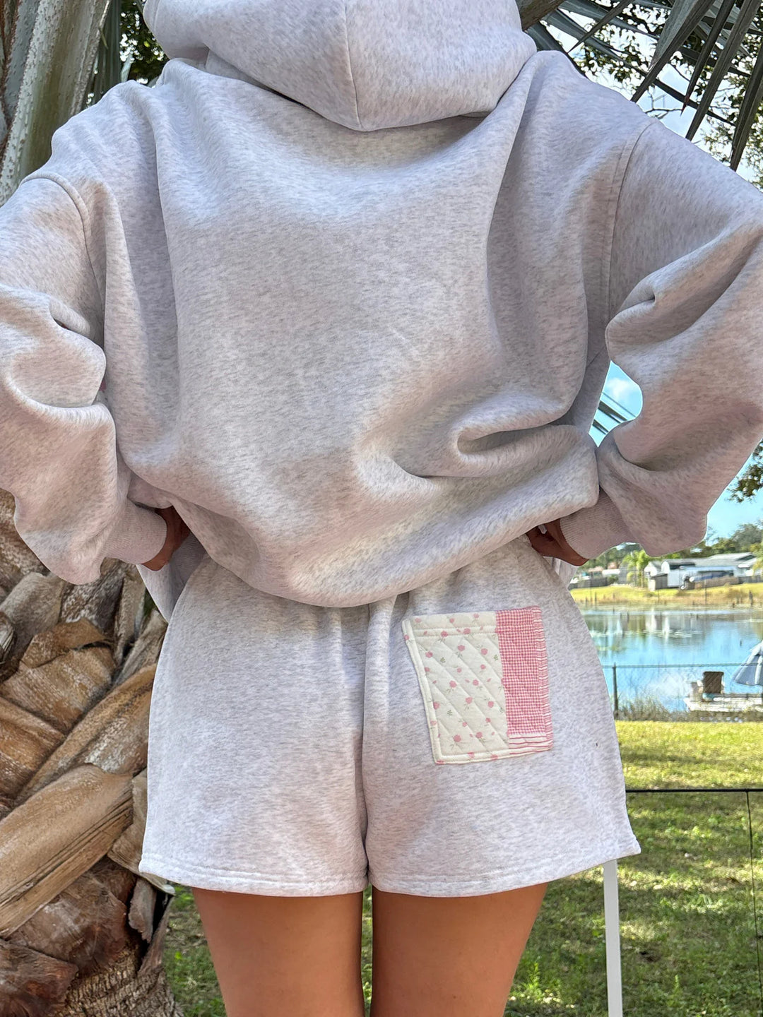 Back of person wearing grey sweat shorts and sweatshirt outdoors