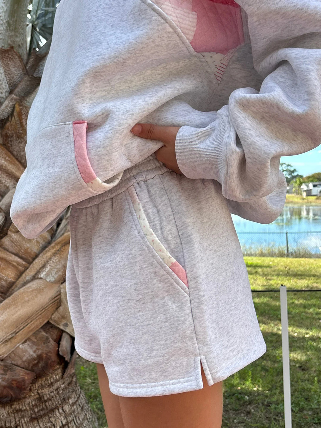 Person wearing grey sweat shorts and sweatshirt outdoors