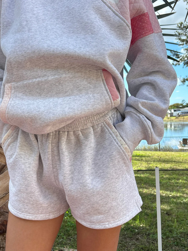 Person wearing grey sweat shorts and sweatshirt outdoors