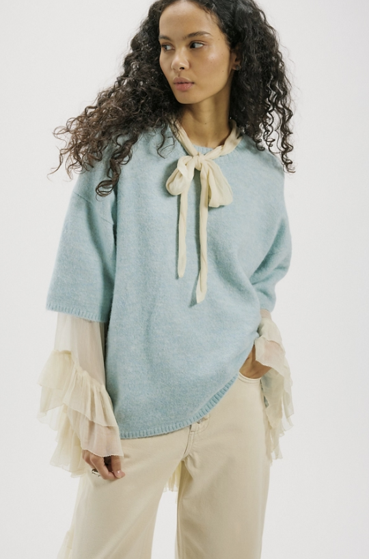 Woman wearing light blue sweater tee with khaki shirt and pants on white background