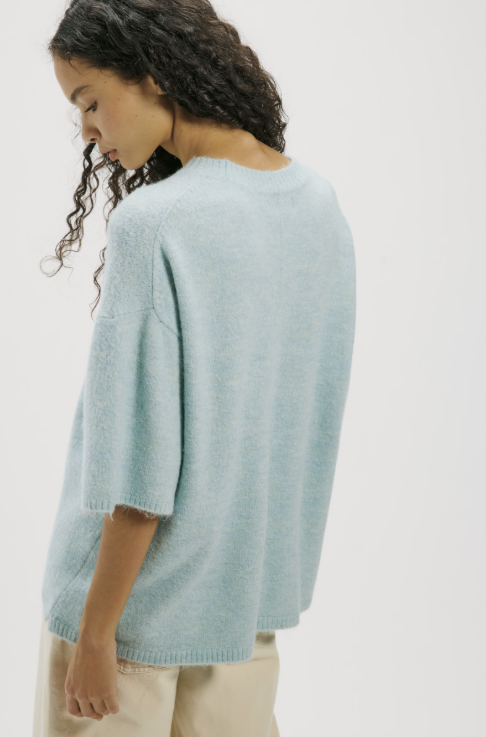 Woman wearing light blue sweater tee on white background