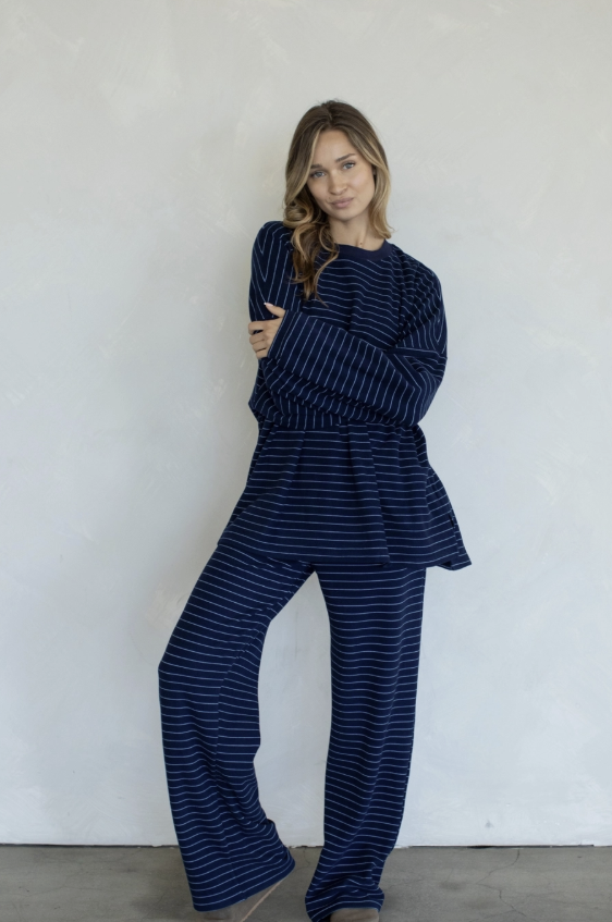 Woman wearing a blue striped outfit against a white wall