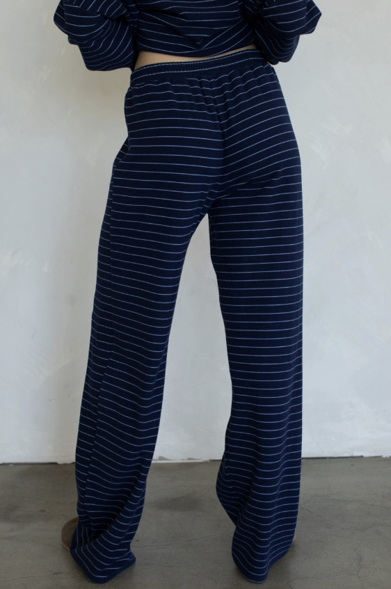 A person shown from the back wearing loose, wide-leg pants and a matching striped top, standing against a plain off-white wall.