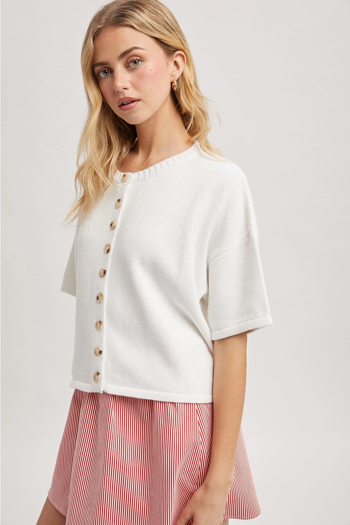 Woman wearing white button up cardigan with red skirt on plain background
