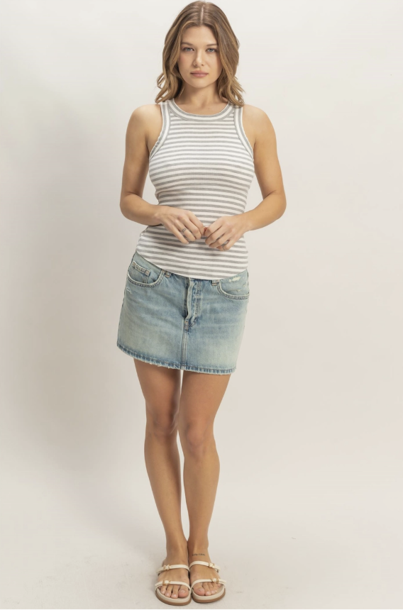Woman wearing a striped tank top and denim skirt on a plain background