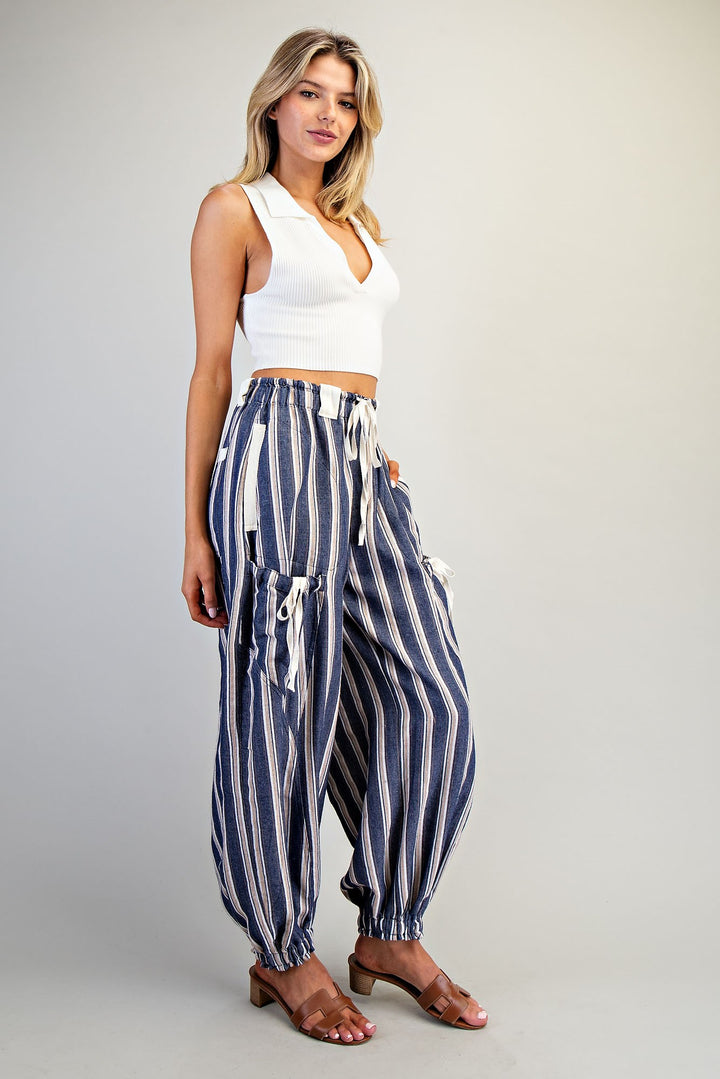 Woman wearing blue stripe pants and white tank on plain background