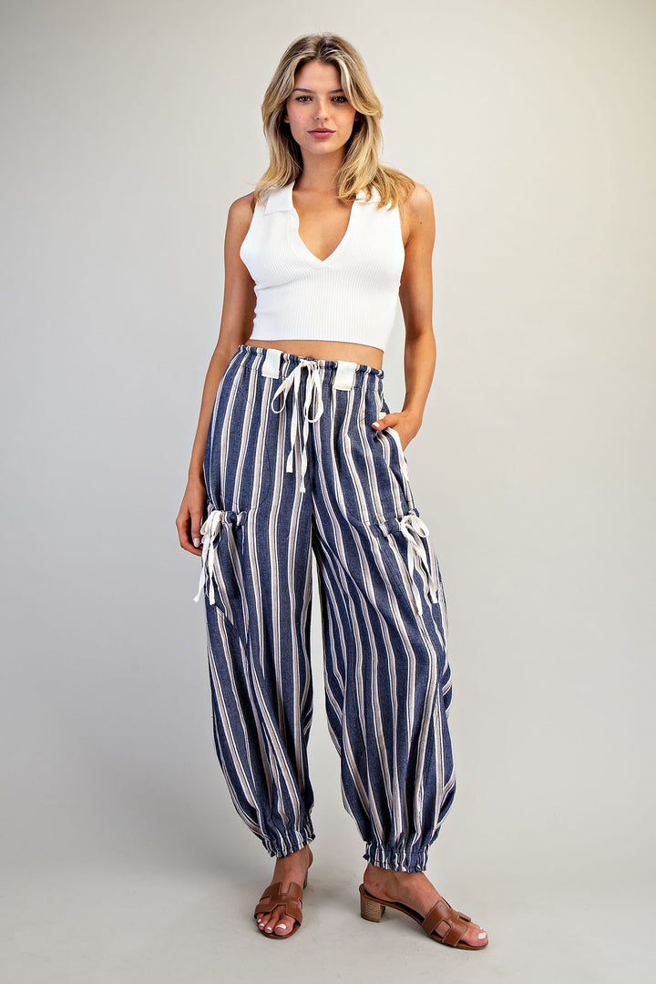 Woman wearing blue stripe pant and white tank on plain background