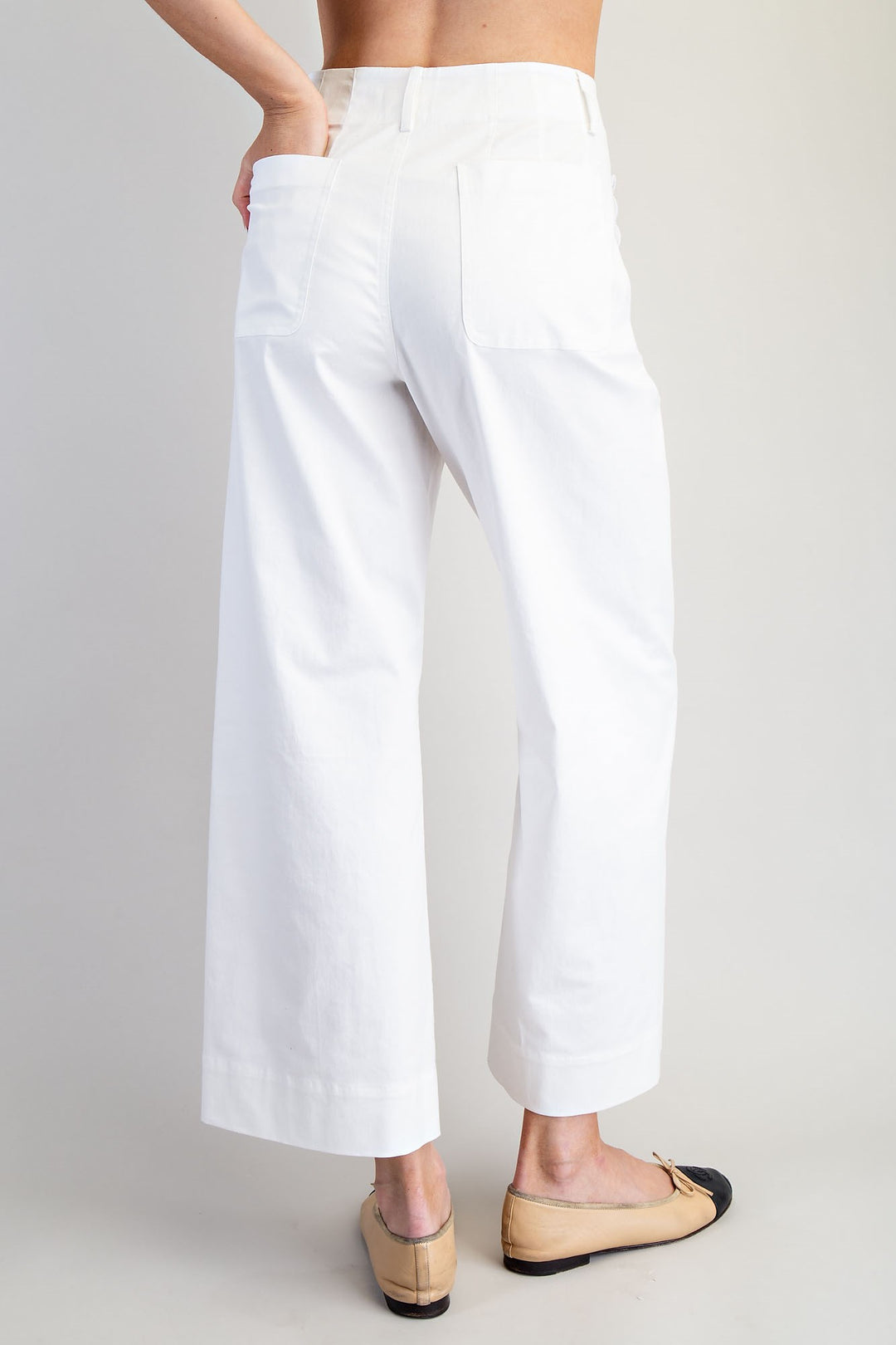White pants worn by a person on a plain background