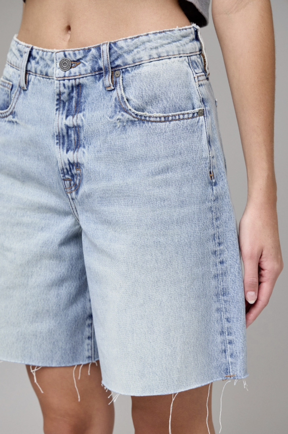 Light blue denim shorts worn by a person on a gray background