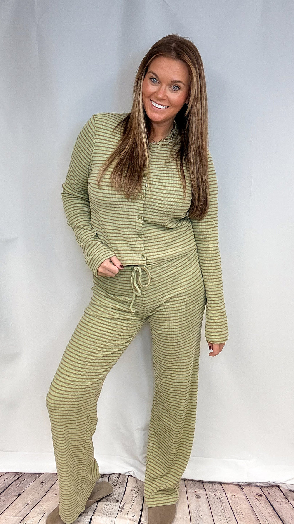Woman wearing matching green stripe set on plain background
