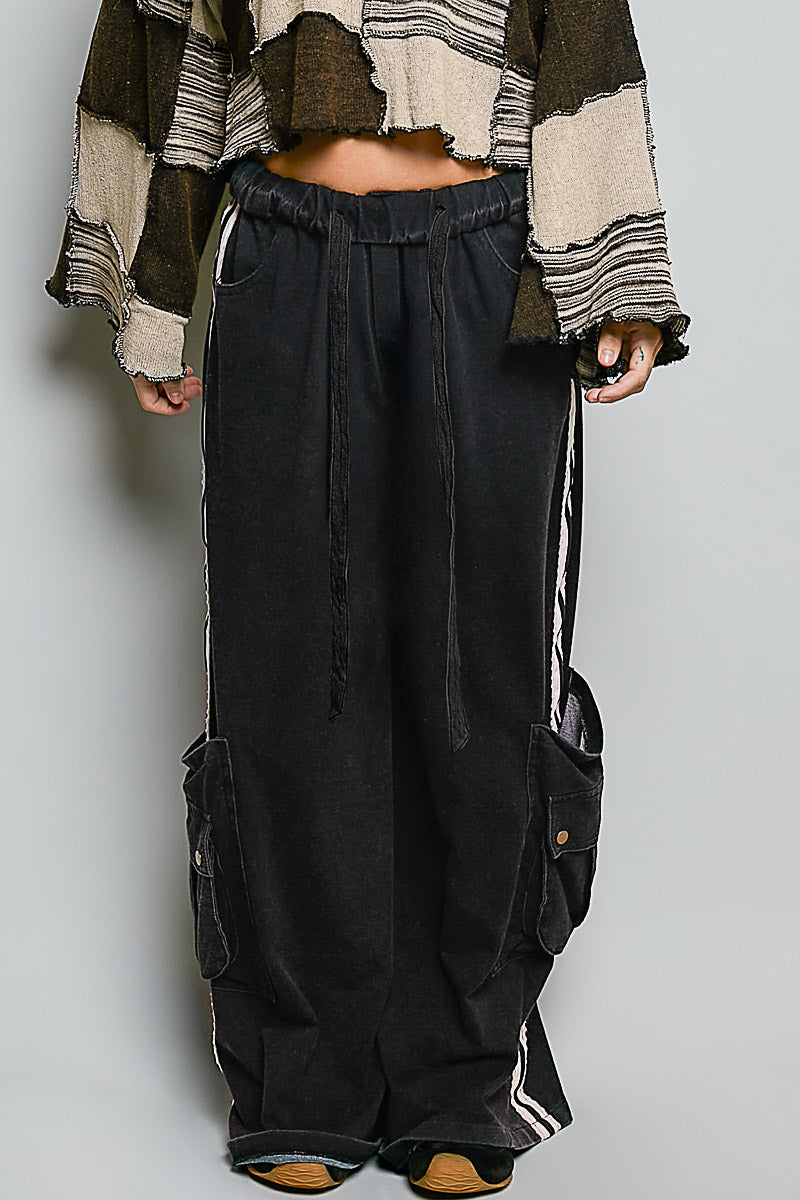 Person wearing a patterned shirt and black cargo pants on a plain background