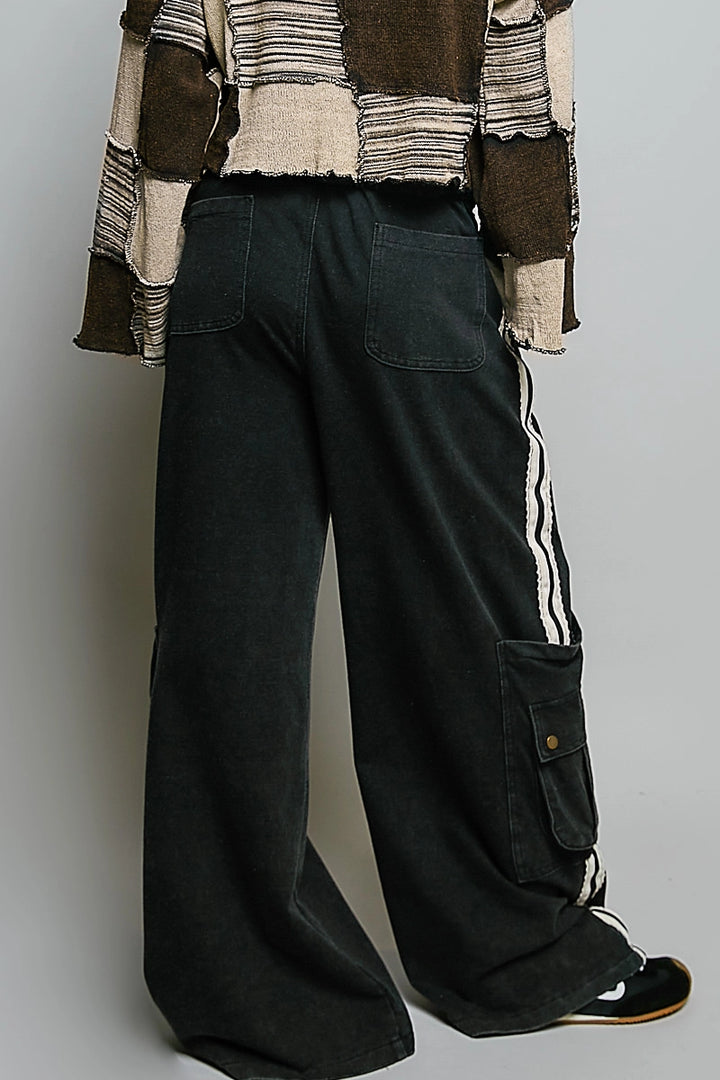 back of person wearing black cargo pants on plain background