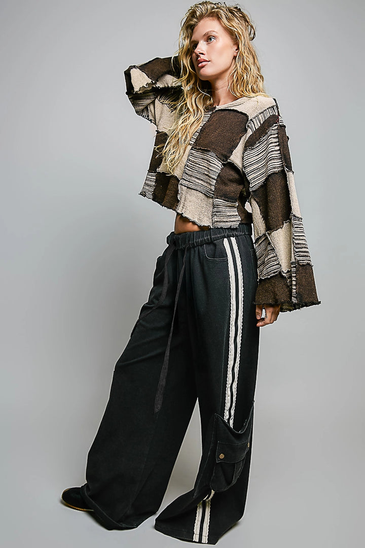 woman wearing black cargo pants and patchwork top on plain background