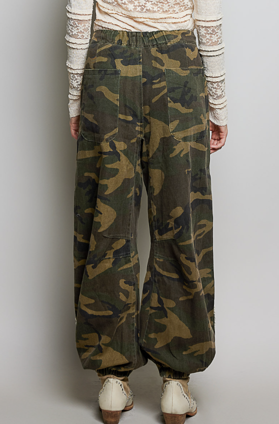 Woman wearing camo pants on plain background