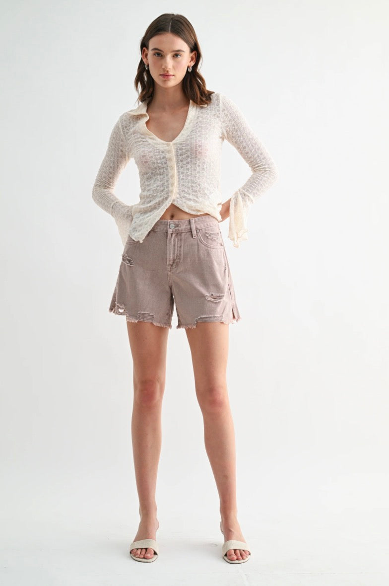 Woman wearing a white knit cardigan and beige shorts on a white background