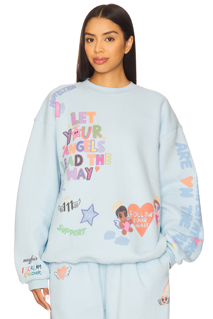 Woman wearing blue graphic sweatshirt on plain background