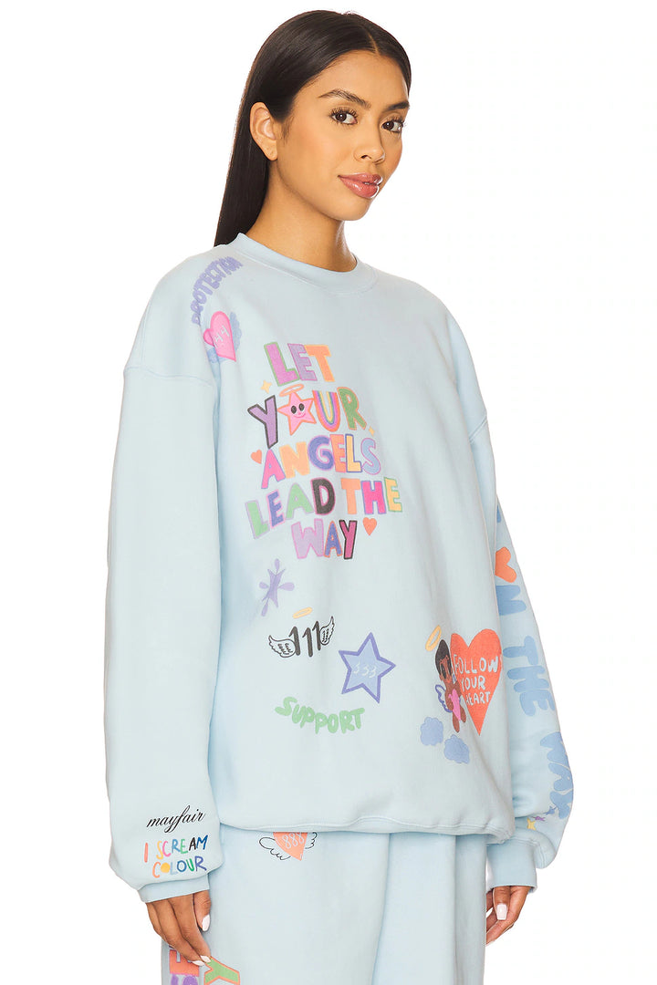 Light blue sweatshirt with colorful text and graphics worn by a model on a white background