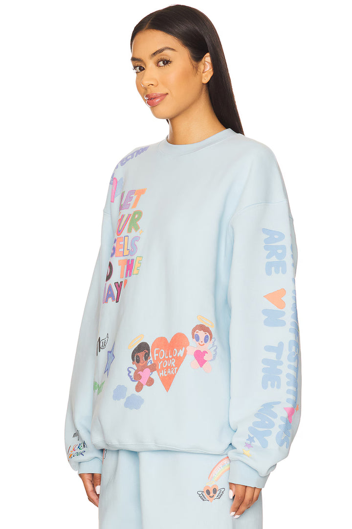 Light blue sweatshirt with colorful graphics and text worn by a model on a white background