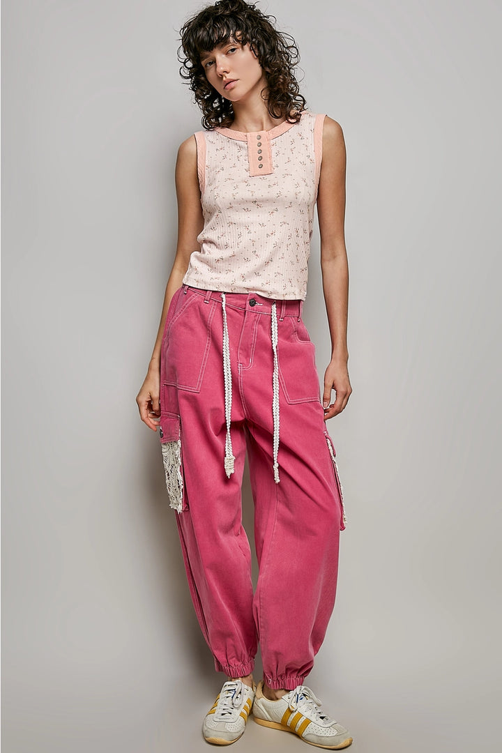 Woman wearing a light pink sleeveless top and bright pink pants against a plain background