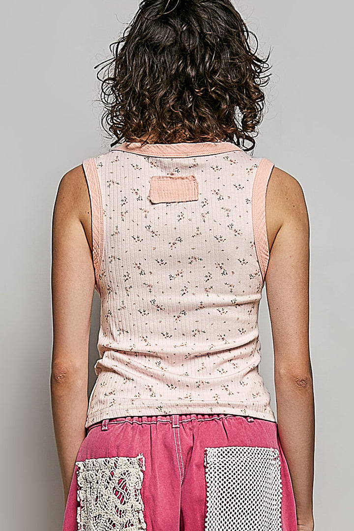 Person wearing a sleeveless floral top and pink pants with lace details on a gray background