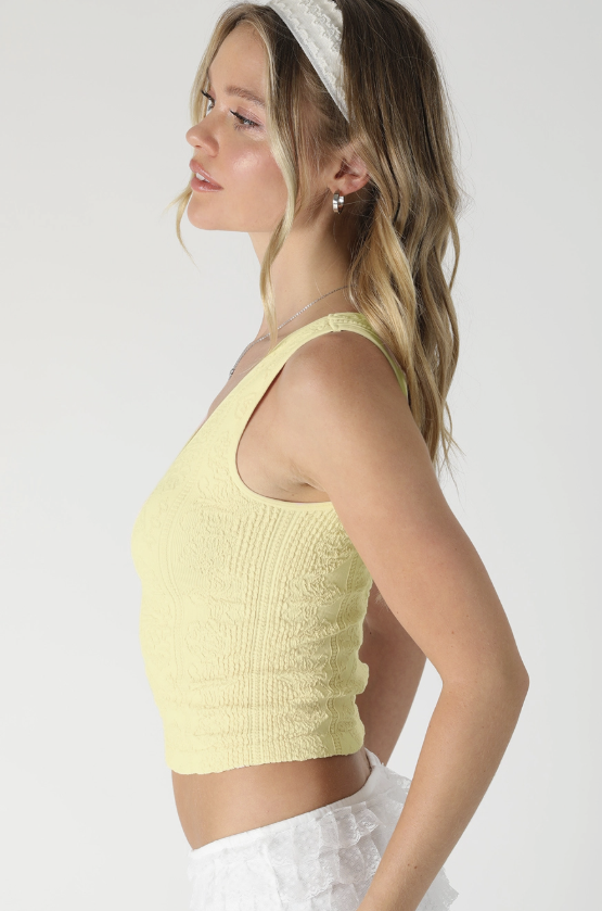 Woman wearing yellow lace top on white background