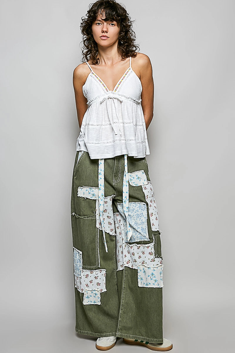 Woman wearing a white top and green patchwork skirt on a plain background