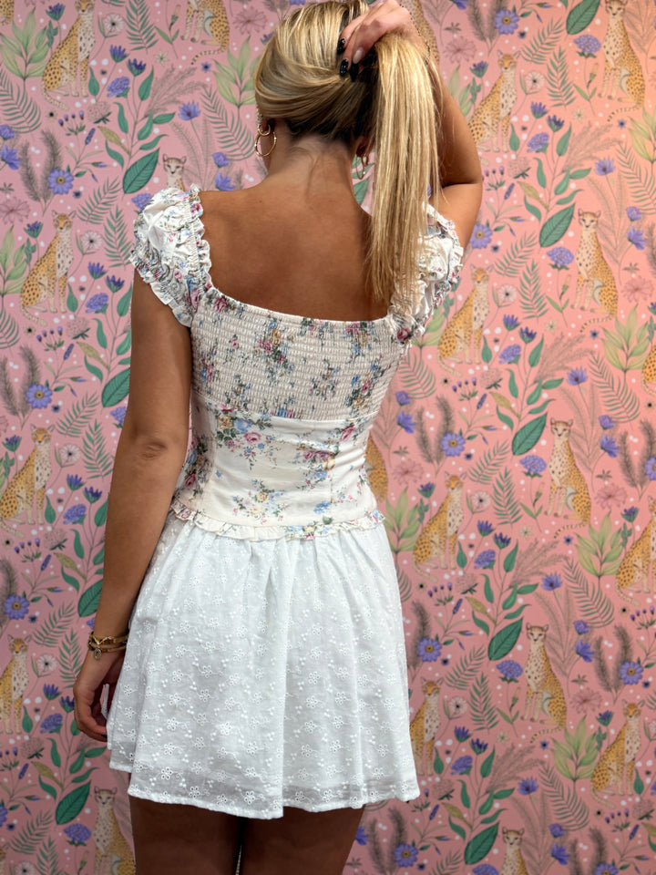 Woman in a white floral dress against a pink patterned wall