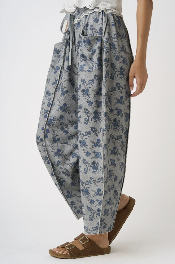 Woman wearing grey floral pants on white background