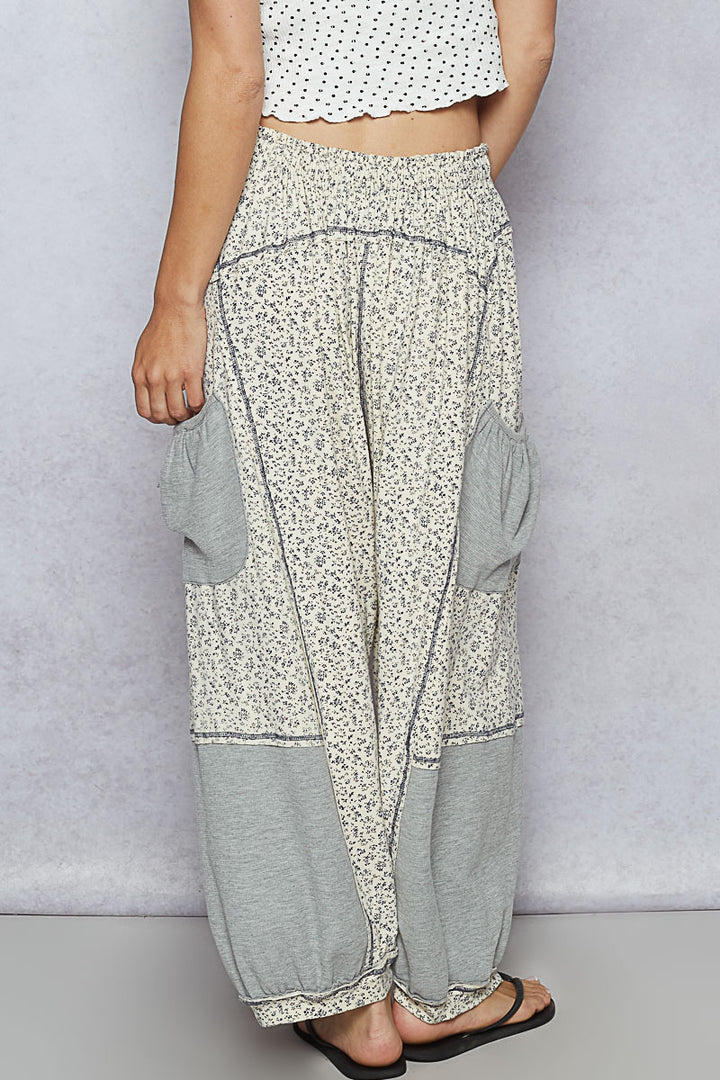 Person wearing a pair of wide-leg pants with floral pattern on a plain background