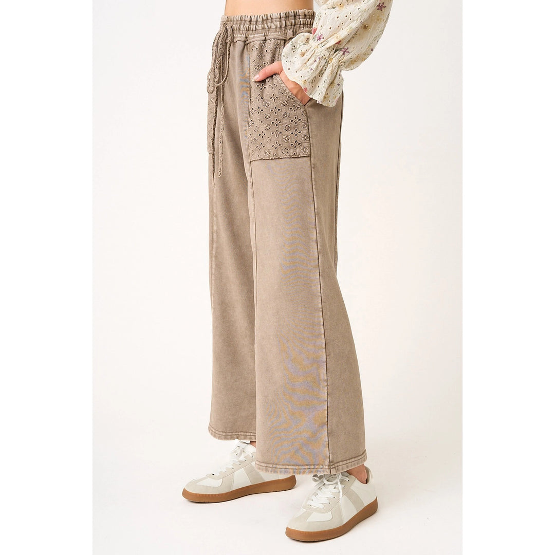 Beige wide-leg pants with lace detailing worn by a person on a white background