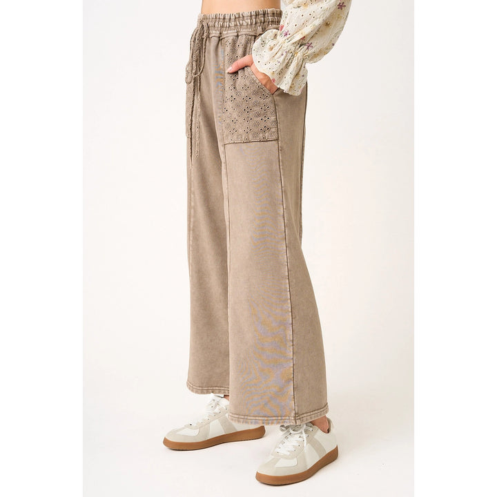 Beige wide-leg pants with lace detailing worn by a person on a white background