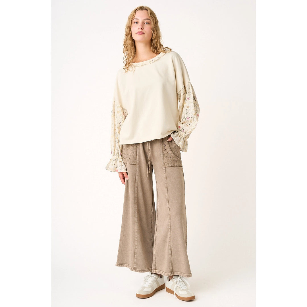 Woman wearing a beige top and wide-leg pants on a white background