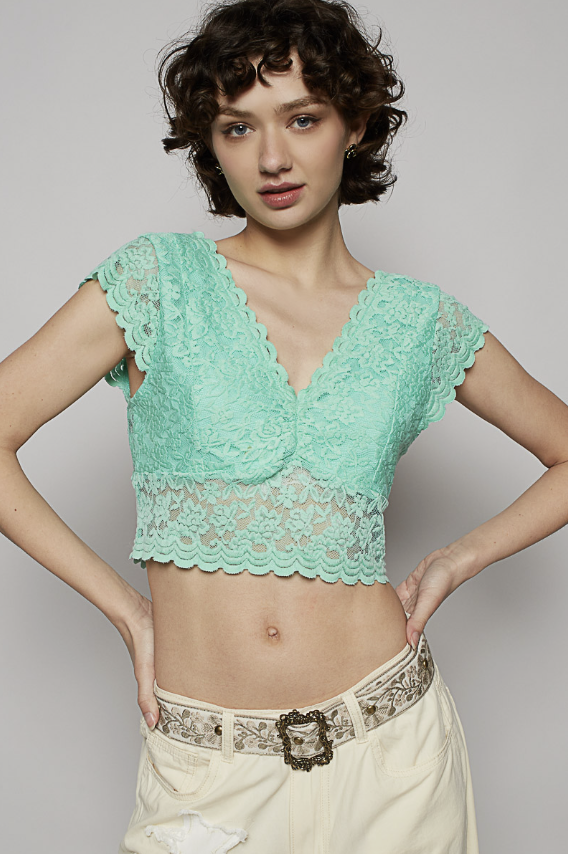 Woman wearing a green lace top against a plain background
