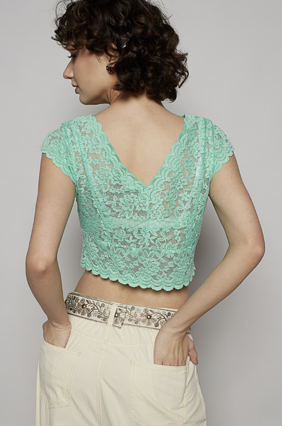 Woman wearing a green lace top against a plain background