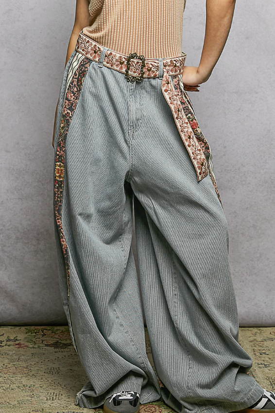 Person wearing wide-leg jeans with a decorative belt against a neutral background