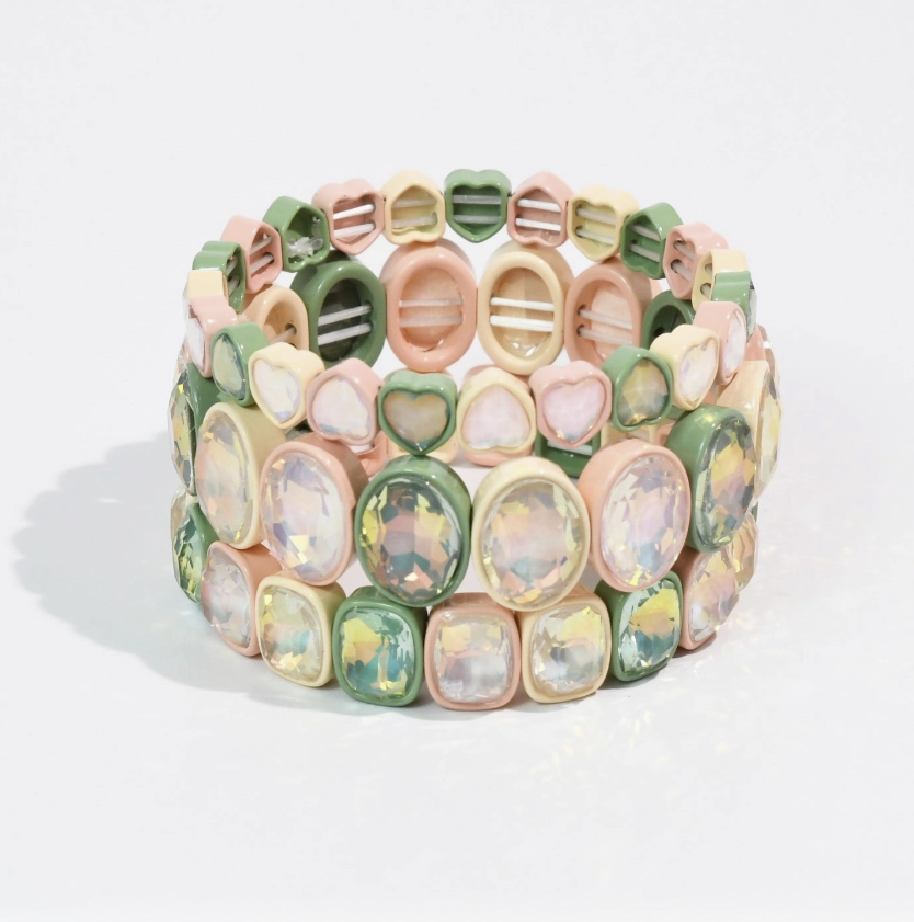 Stack of three bracelets with iridescent gemstones with green, pink and ivory tiles on white background