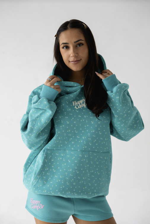 Woman wearing a teal hoodie and shorts set with 'Happy Camp' text on a white background