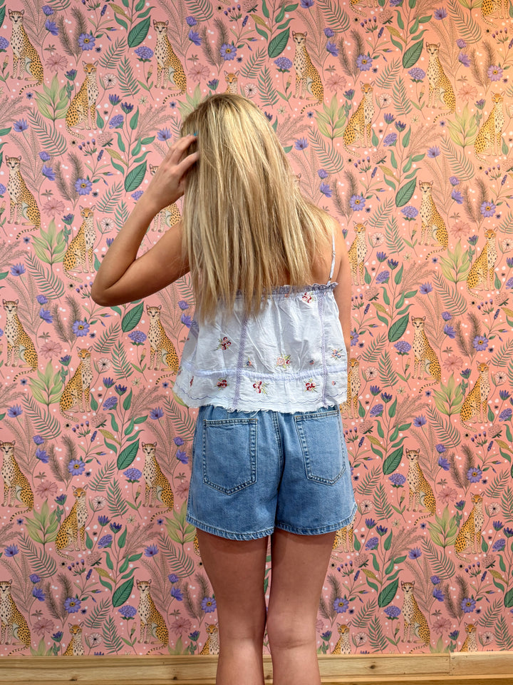 Person standing in front of a pink floral wallpapered wall