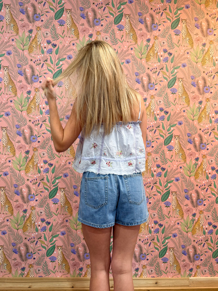 Person standing in front of a wall with a pink floral and animal pattern