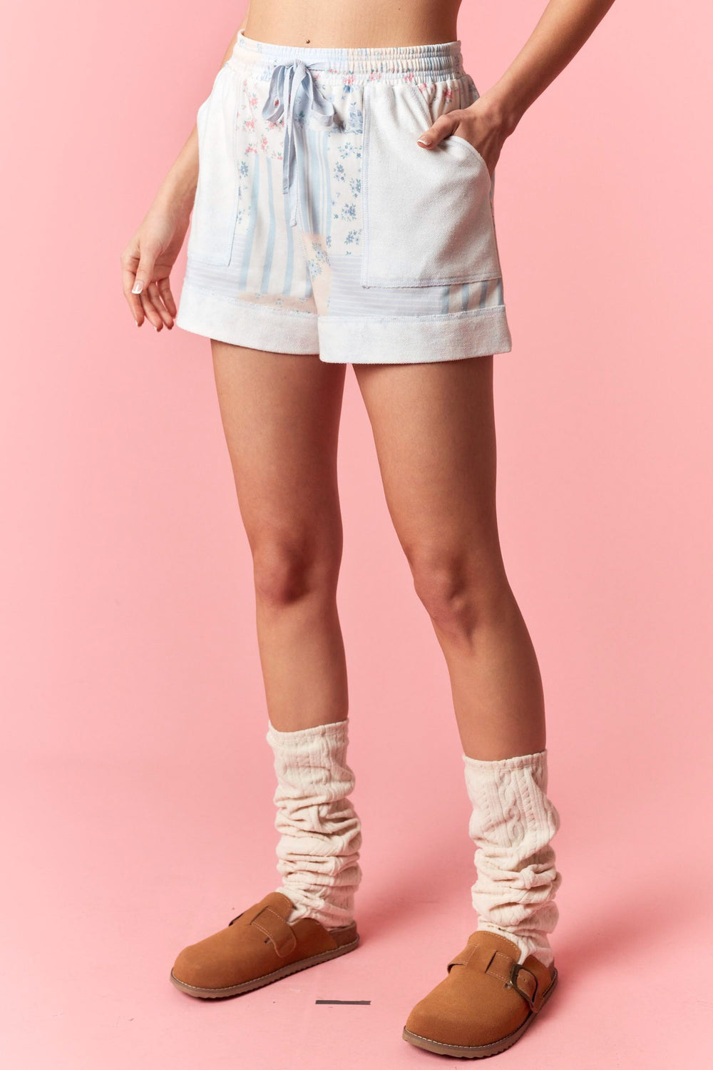 Woman wearing blue floral patchwork shorts on pink background