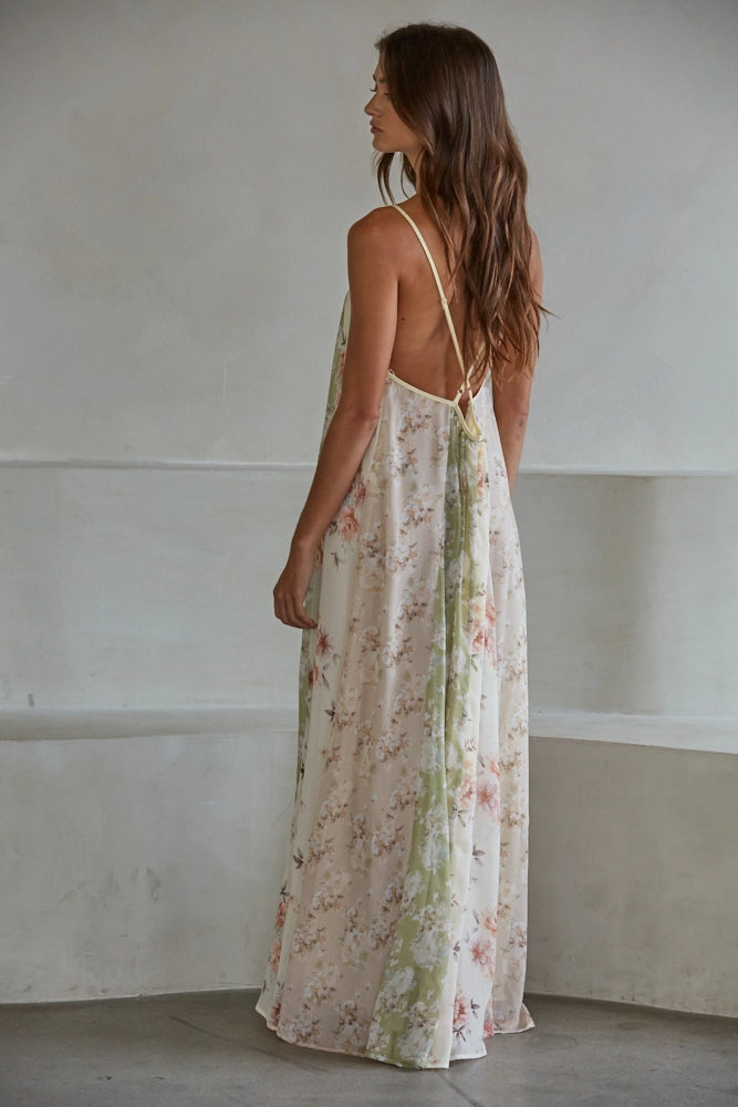 Back of woman wearing floral print maxi dress on plain background